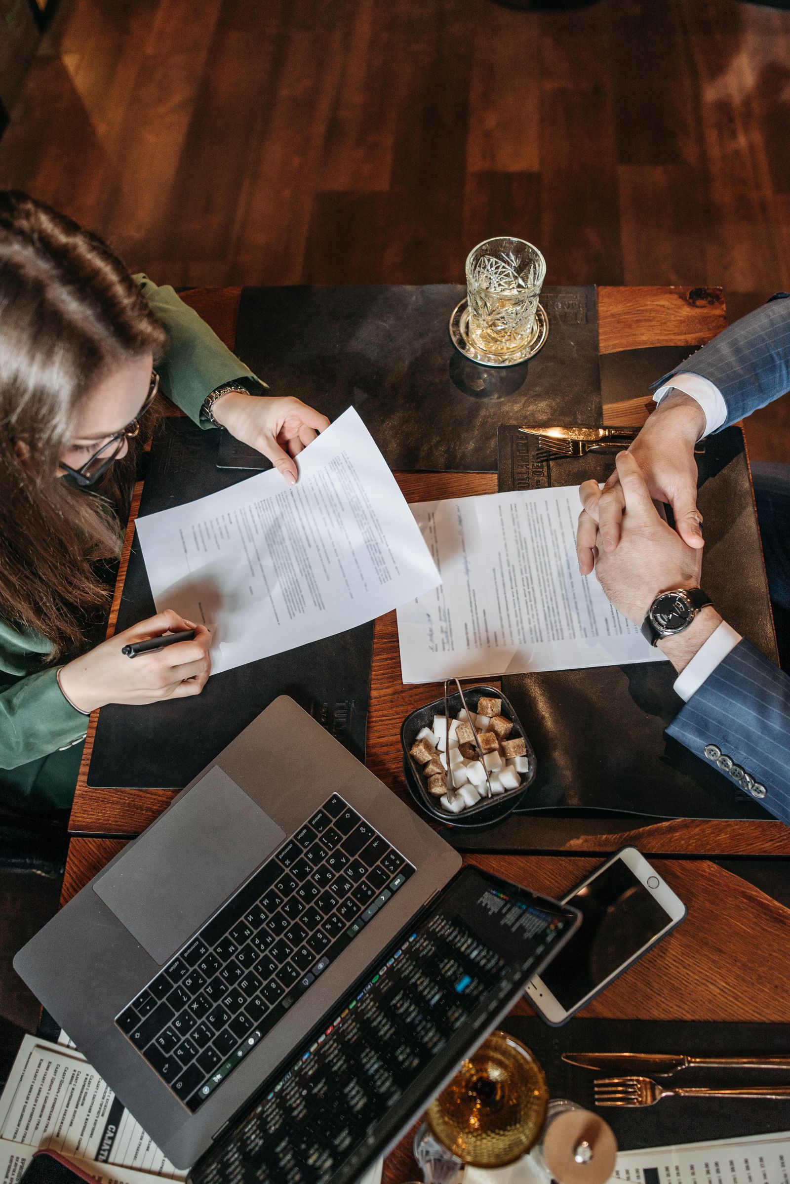 People reviewing and signing documents beside a laptop